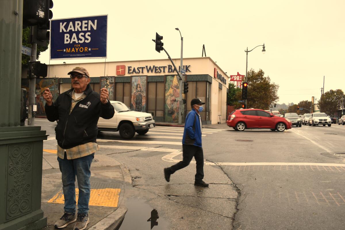 Rosalio Muñoz, a Karen Bass supporter, holds up a sign at North Broadway and Daly Street in Lincoln Heights.