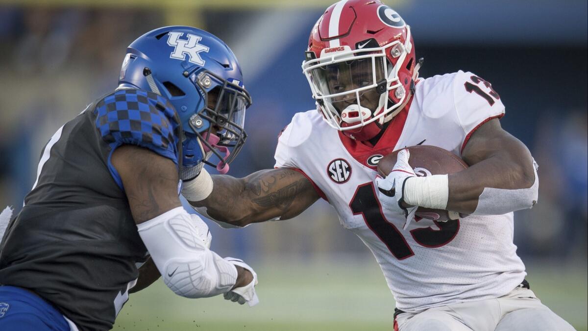 Georgia running back Elijah Holyfield (13) stiff arms Kentucky safety Mike Edwards (7) during the second half on Saturday.