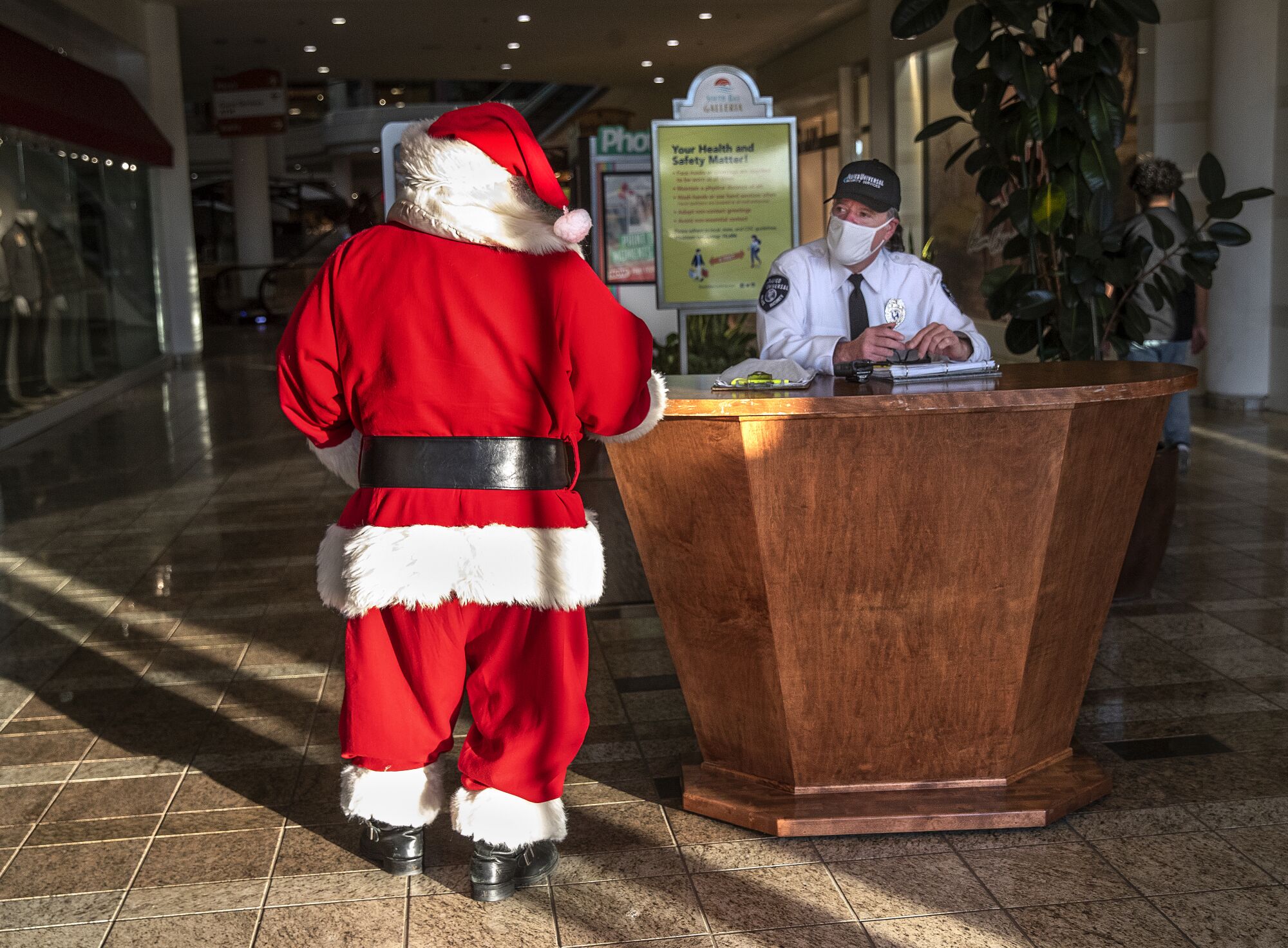 Santa walks past a mall security guard