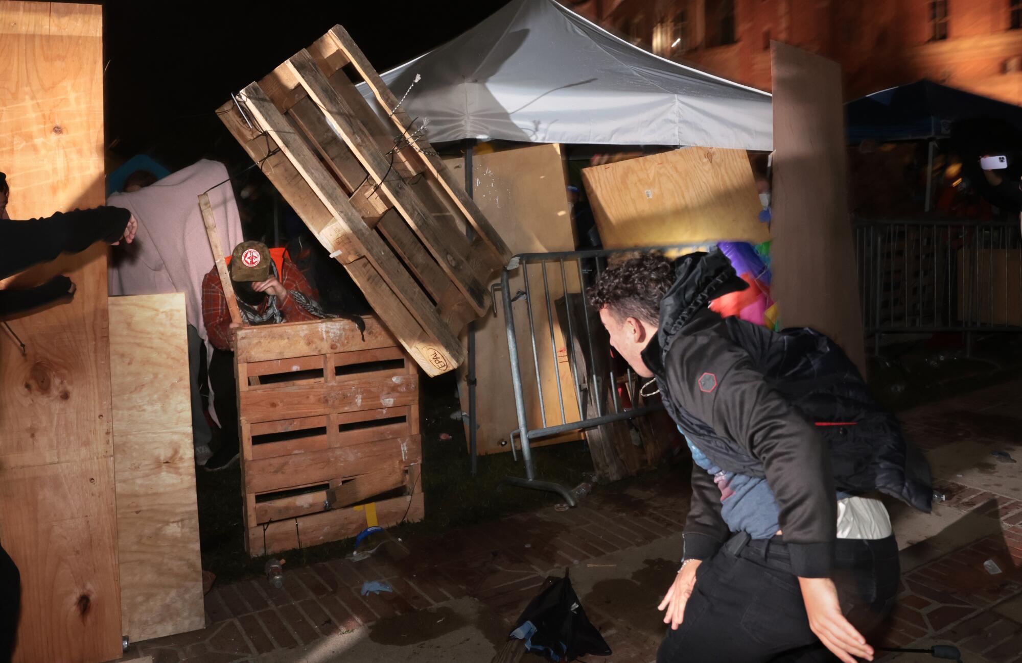 A counterprotester throws a pallet at a barricade.