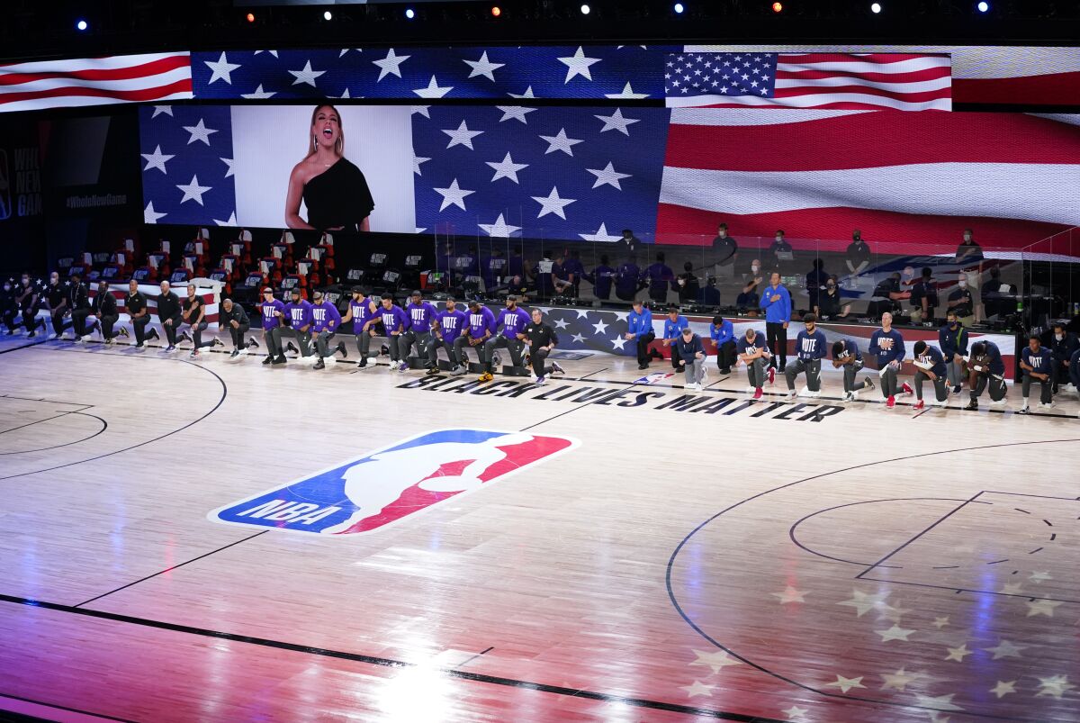 Players and coaches kneel on the floor during the national anthem before Game 2.