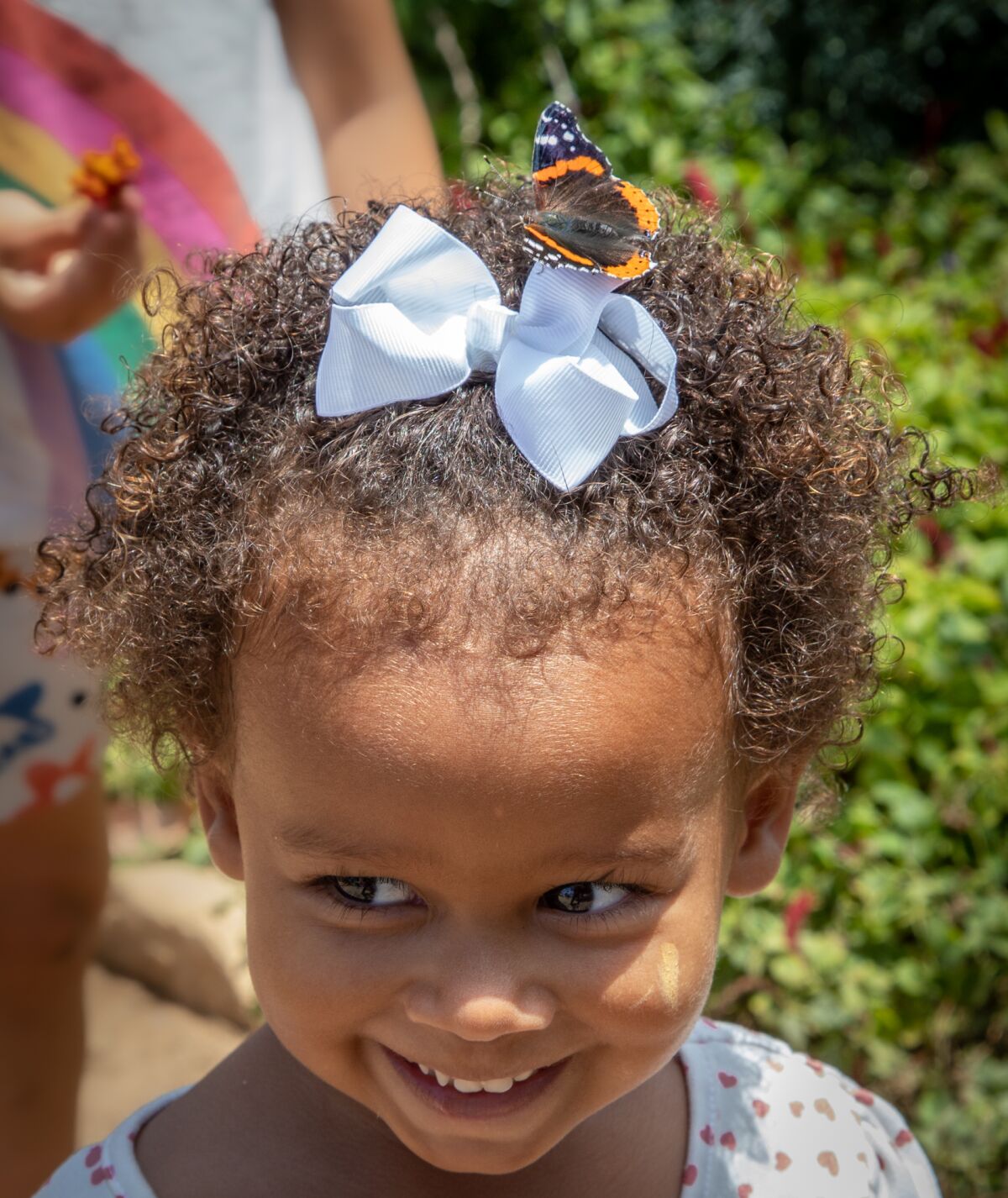 Natasha Rivera, 2, of Oceanside smiles as a red admiral butterfly takes a rest on her hair bow.