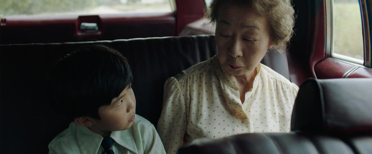 Alan Kim as David and Yuh-Jung Youn as his grandmother Soonja sit in a car.