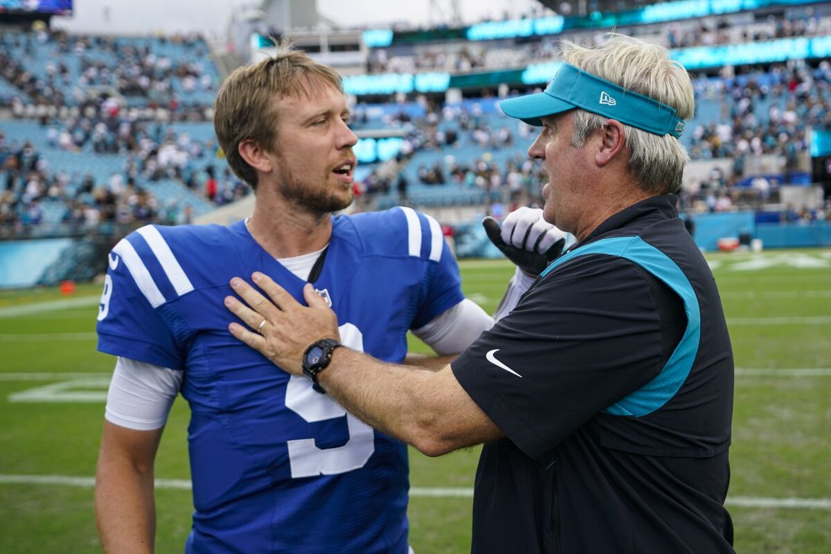 Jacksonville Jaguars head coach Doug Pederson meets with Indianapolis Colts quarterback Nick Foles (9) following an NFL football game, Sunday, Sept. 18, 2022, in Jacksonville, Fla. The Jaguars defeated the Colts 24-0. (AP Photo/John Raoux)