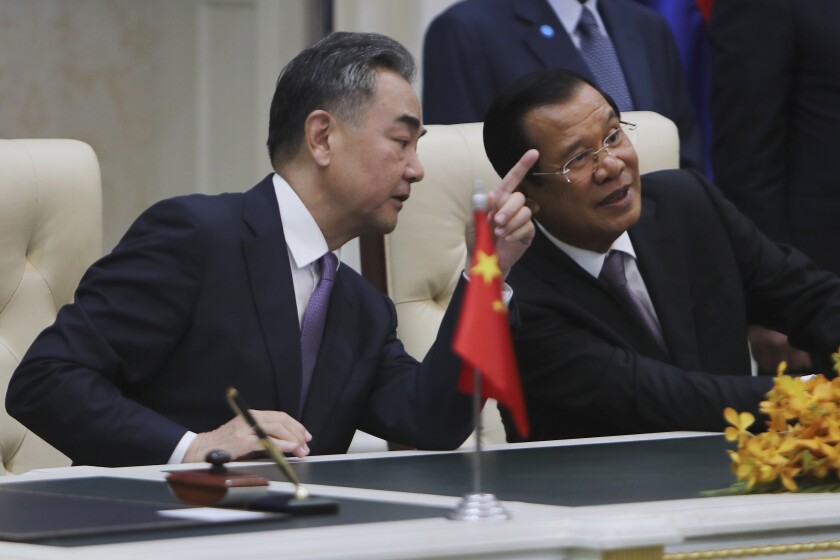 FILE - Chinese Foreign Minister Wang Yi, left, talks with Cambodian Prime Minister Hun Sen as they sit to witness a signing ceremony for a free trade agreement at Peace Palace in Phnom Penh, Cambodia, Monday, Oct. 12, 2020. The U.S. has ordered an arms embargo on Cambodia, citing deepening Chinese military influence, corruption and human rights abuses by the government and armed forces in the Southeast Asian country. (AP Photo/Heng Sinith, File)