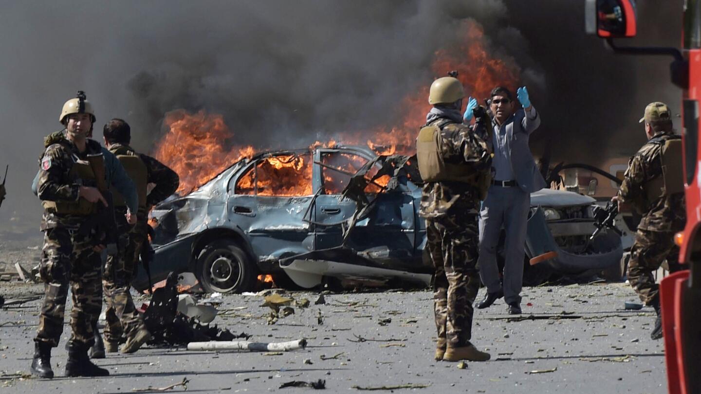 Afghan soldiers keep watch amid burning wreckage and debris after a car bomb exploded in Kabul on Wednesday morning.