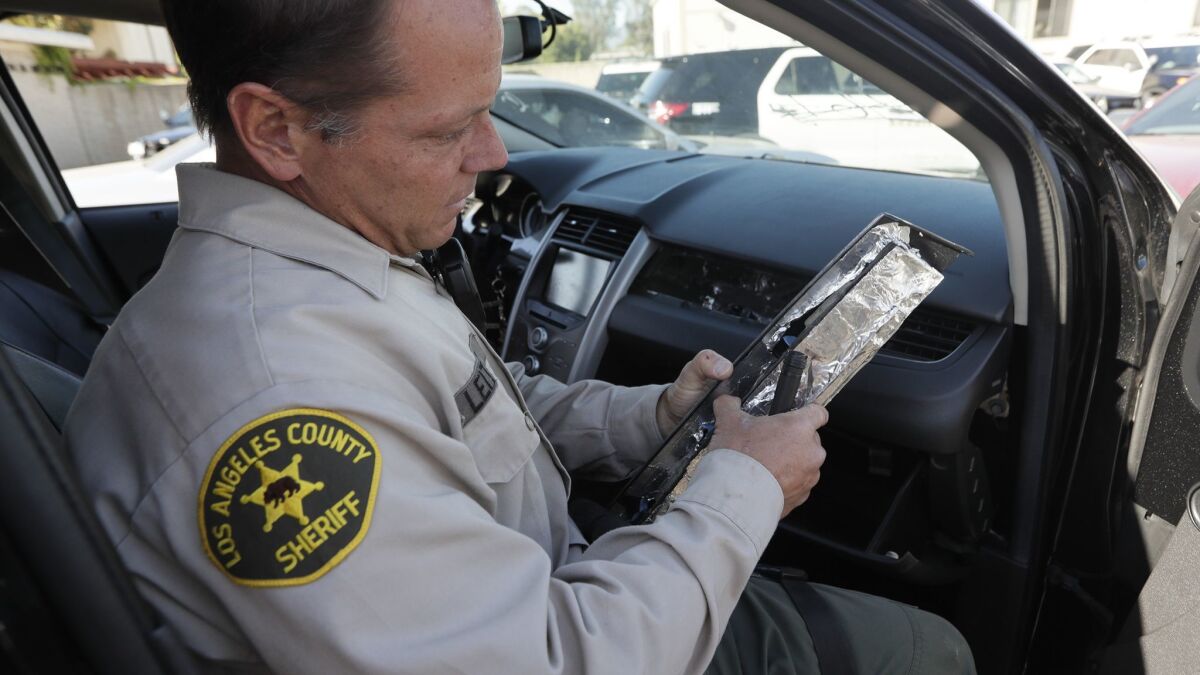 Deputy John Leitelt pulls a piece of a dashboard panel modified to hide drugs in an impounded vehicle.