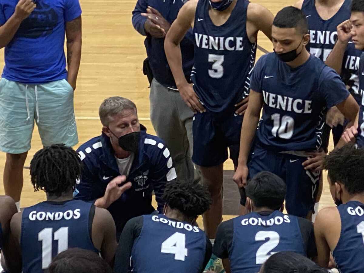 Venice High basketball players surround coach David Galley during a game.