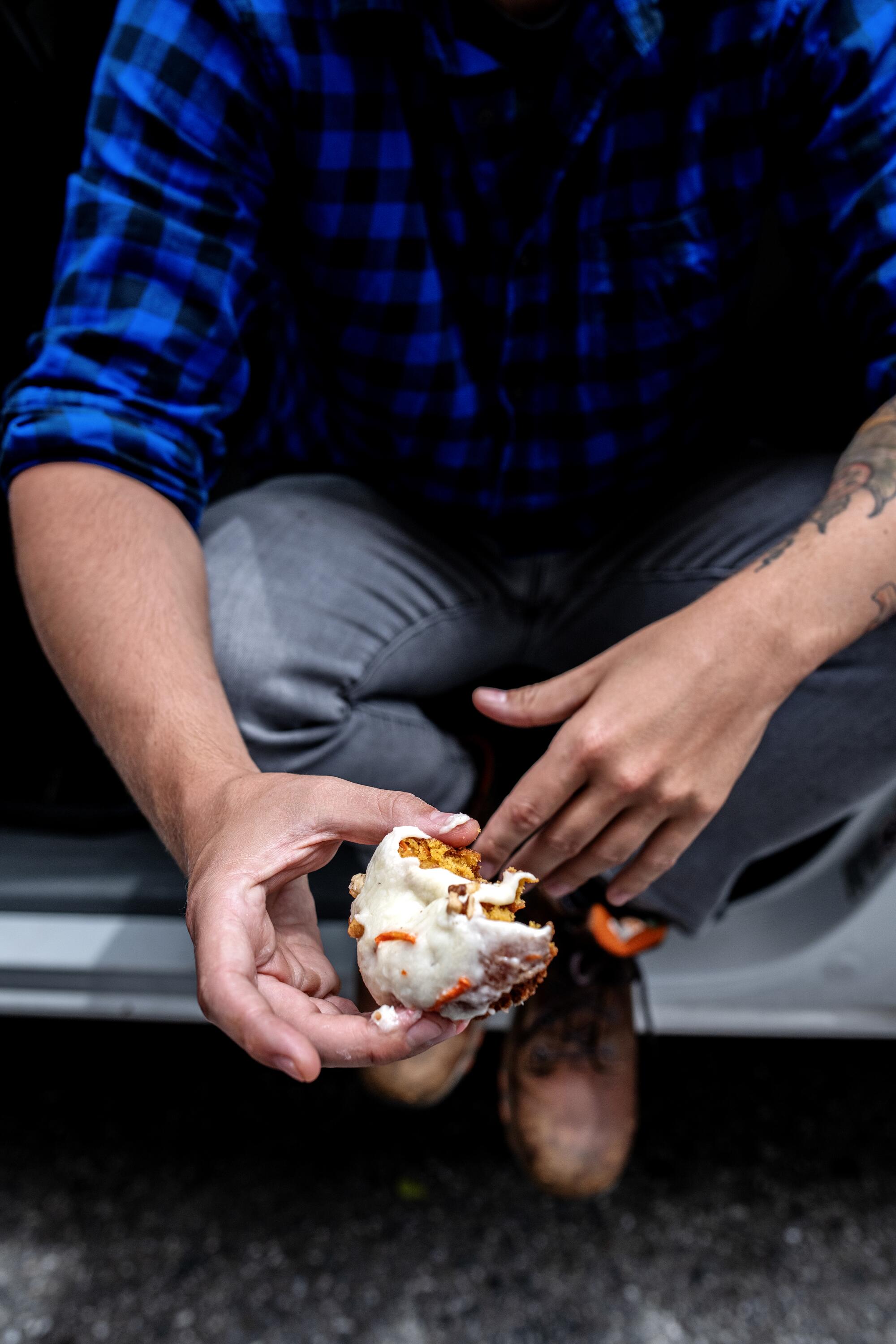 Detail of Danny Palumbo's hand holding a donut as he sits in the drivers' seat of his car, facing outside.