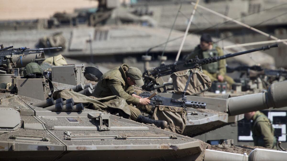 Israeli soldiers work on their tanks at a gathering area near the Israel-Gaza border on Tuesday.