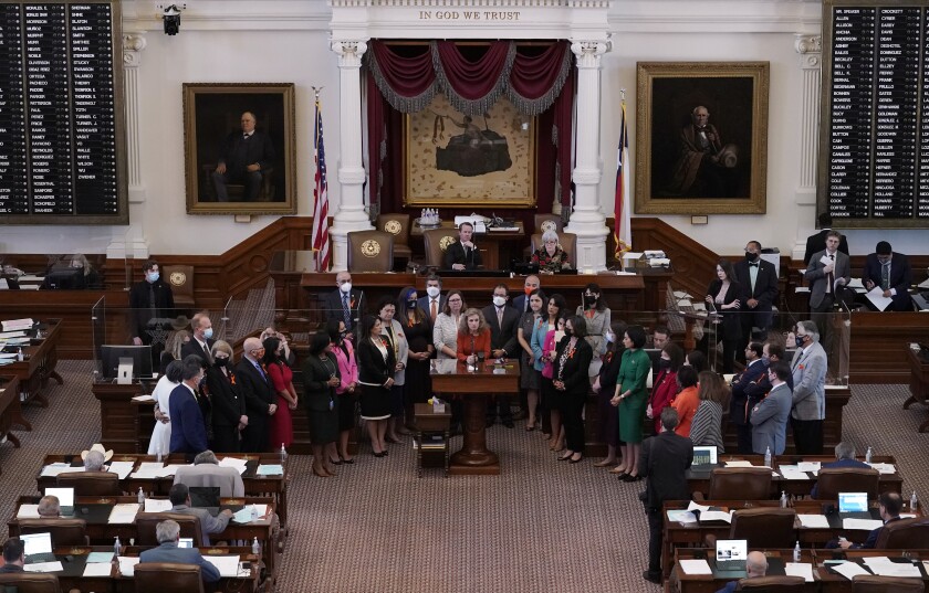 Lawmakers stand together in the House Chamber in Austin, Texas. 