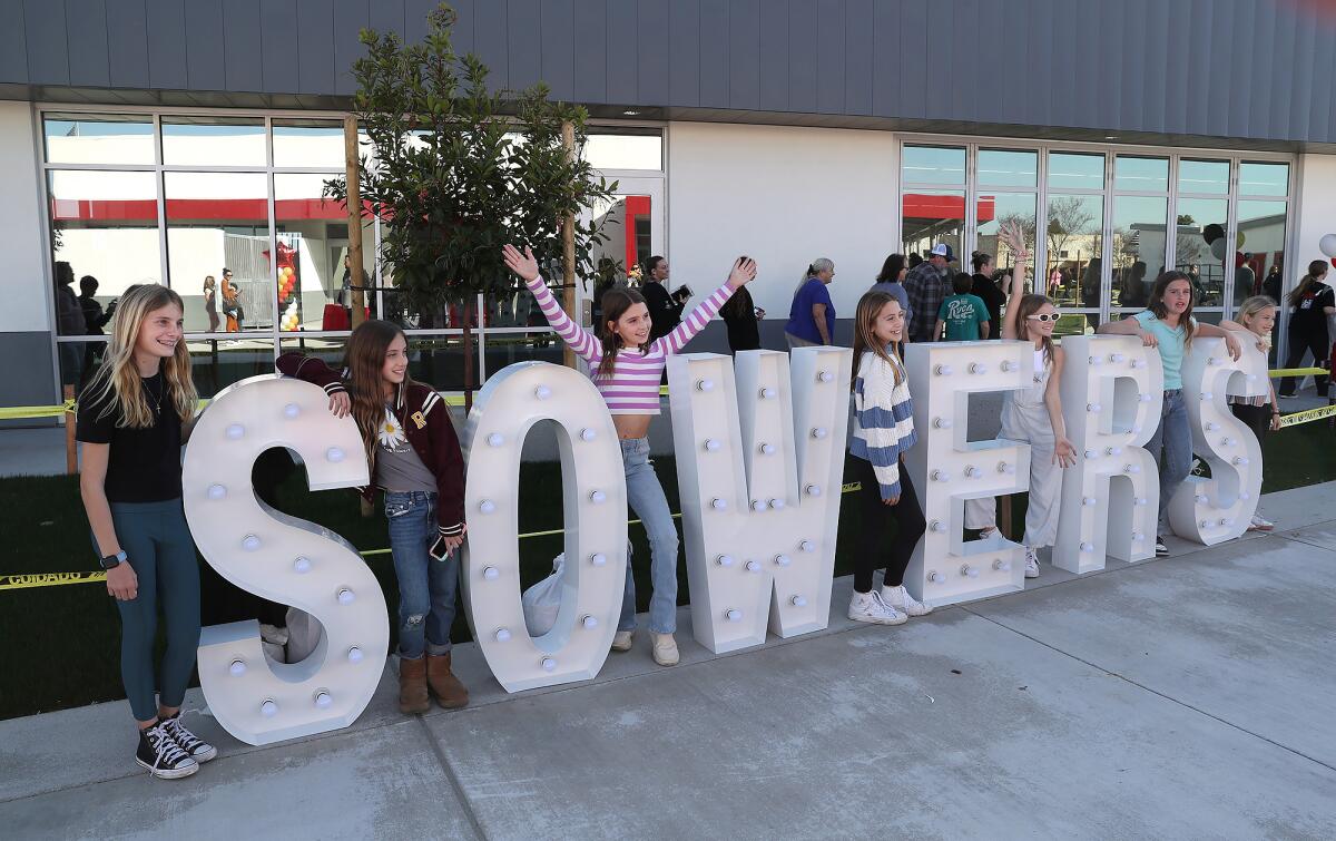 Sowers Middle School students stand between new marquee letters during the school's ribbon-cutting.