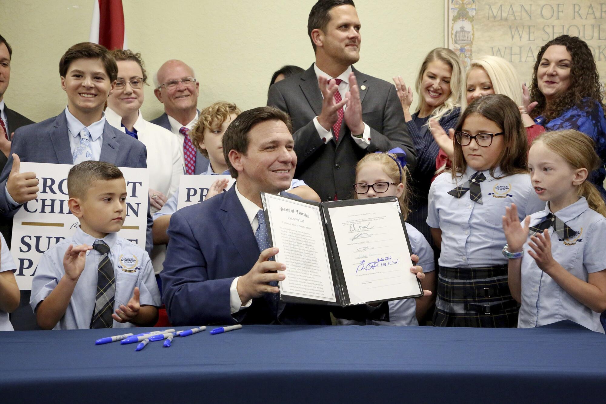 A man displays signed pages while people stand behind him.