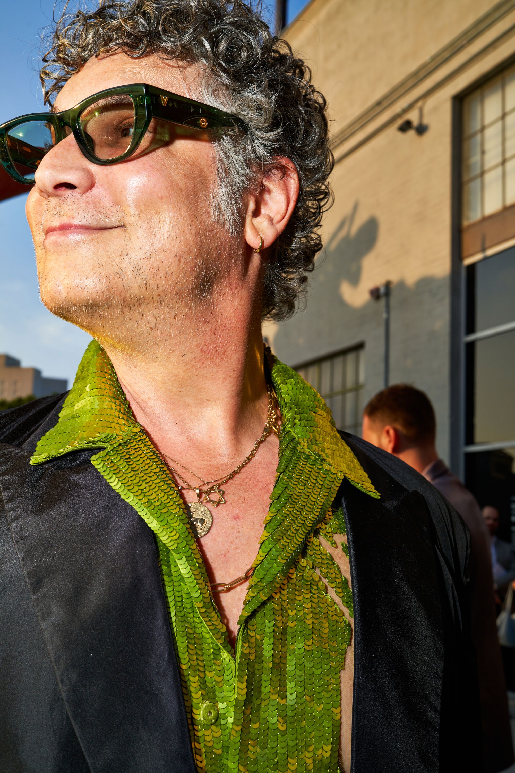 A man in glasses wearing a sparkling green shirt.