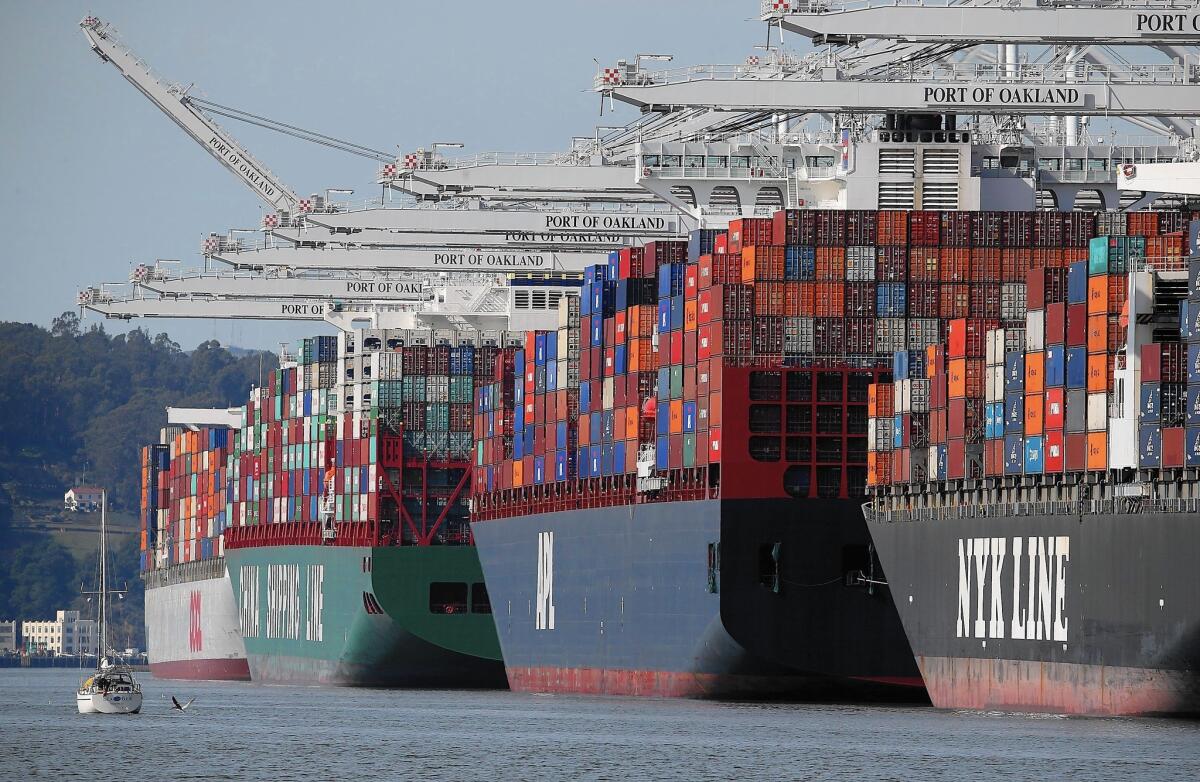 Container ships stacked high with cargo sit moored at the Port of Oakland, one of the West Coast ports that have been affected by a partial shutdown because of a labor dispute.