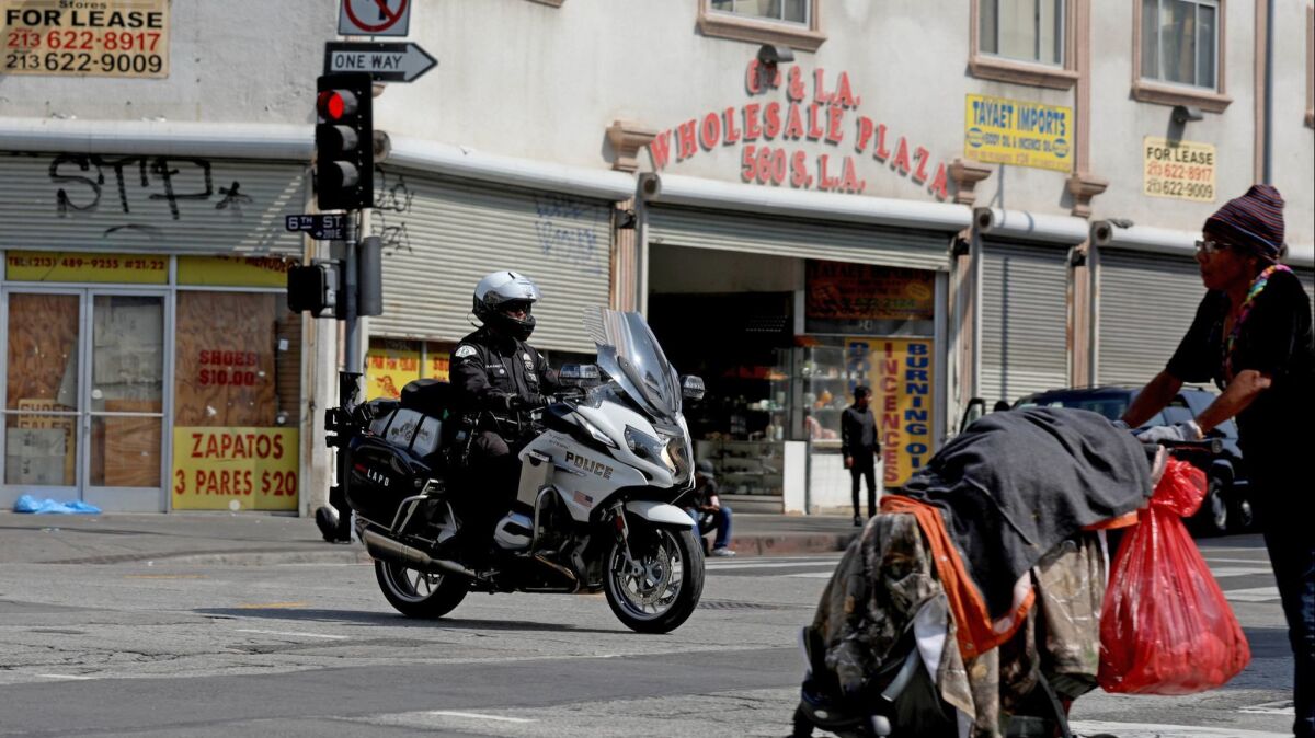 An LAPD motorcycle officer patrols along East 6th Street and Maple Avenue near the LAPD Central Station. At least one but as many as three LAPD detectives at the downtown station have contracted the strain of bacteria that causes typhoid fever, though its origin is unknown.