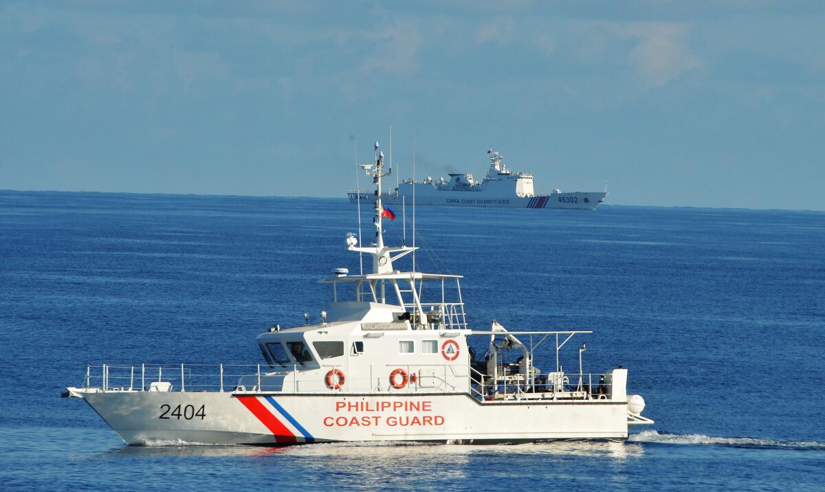 A Philippine coast guard ship passes a Chinese ship in the South China Sea.