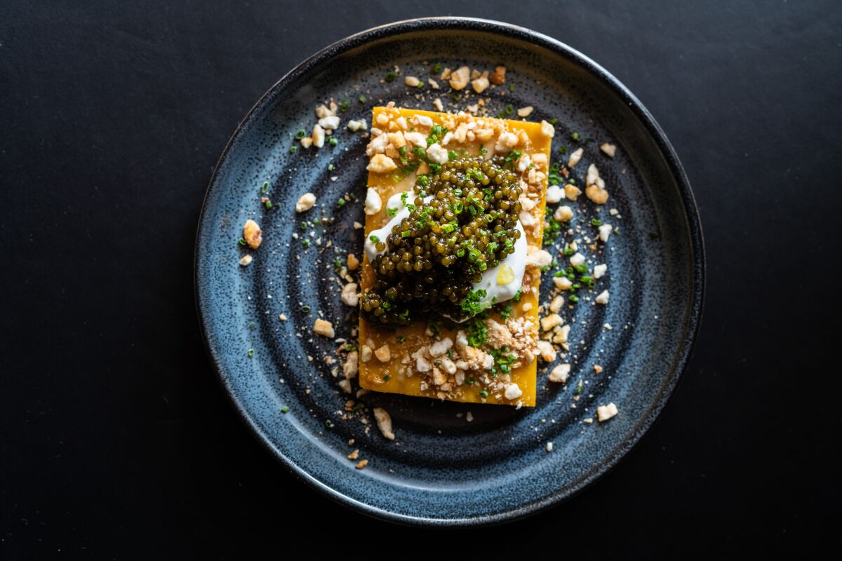 Overhead photo of a tamal topped with caviar on a plate.