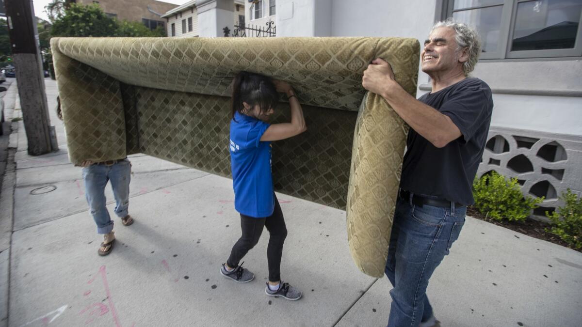 Two years after her eviction, Sylvie Shain, center, moves a sofa back into her apartment at the Villa Carlotta with help from friends Jen Getz, left, and Steve Luftman, right in Hollywood.