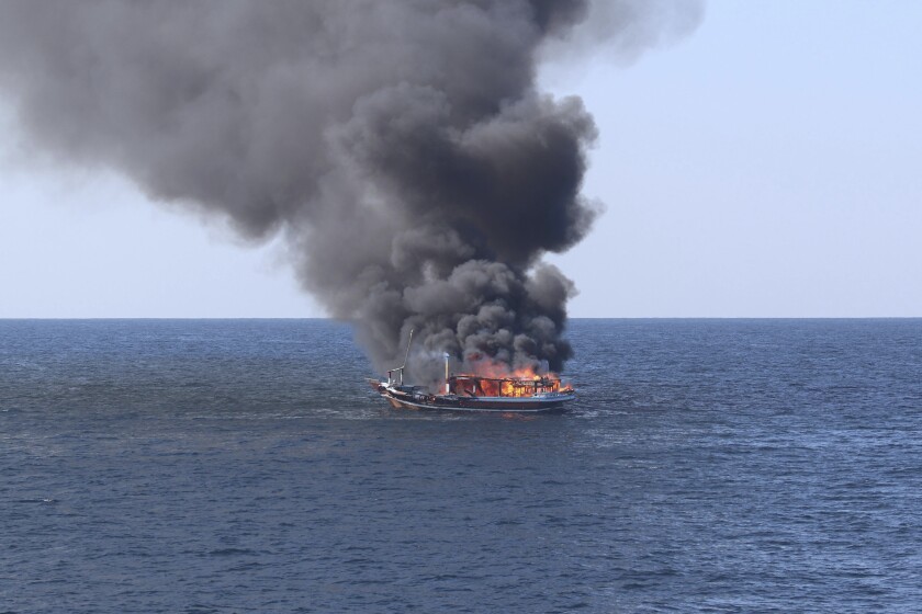 In this handout photograph from the U.S. Navy, a traditional dhow sailing vessel suspected of smuggling drugs burns in the Gulf of Oman on Wednesday, Dec. 15, 2021. The U.S. Navy said Thursday it rescued five Iranians suspected of smuggling drugs after they apparently set fire to their stash on board a traditional sailing vessel off the coast of Oman, though one remains missing. (U.S. Navy via AP)