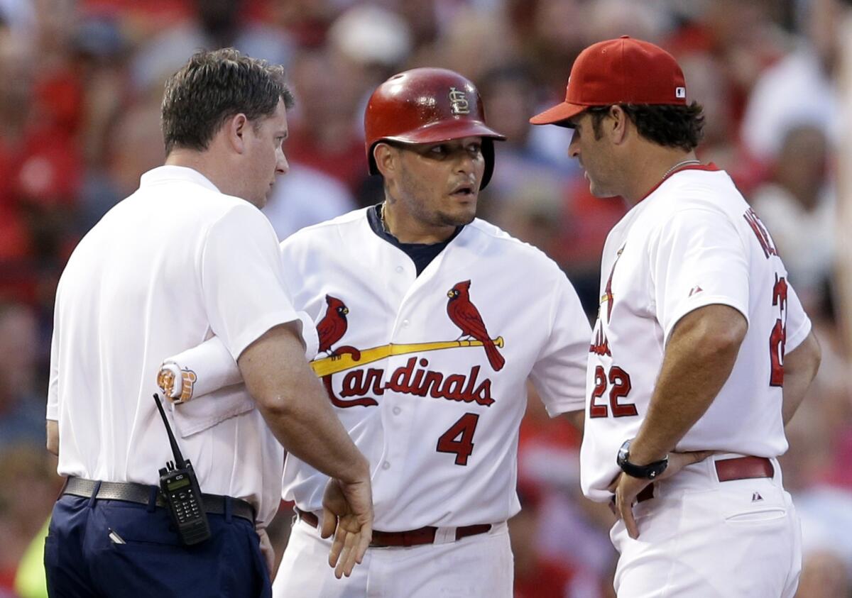 St. Louis catcher Yadier Molina, center, is checked out by trainer Chris Conroy, left, and Manager Mike Matheny after injuring his hand while sliding into third base during a game Wednesday.