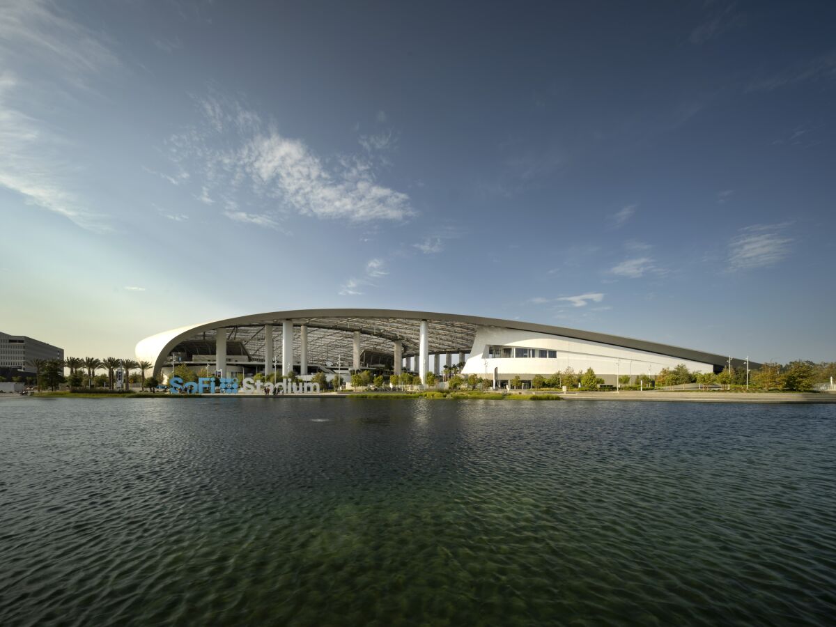 A placid lake sits before a stadium with a curving roof line.