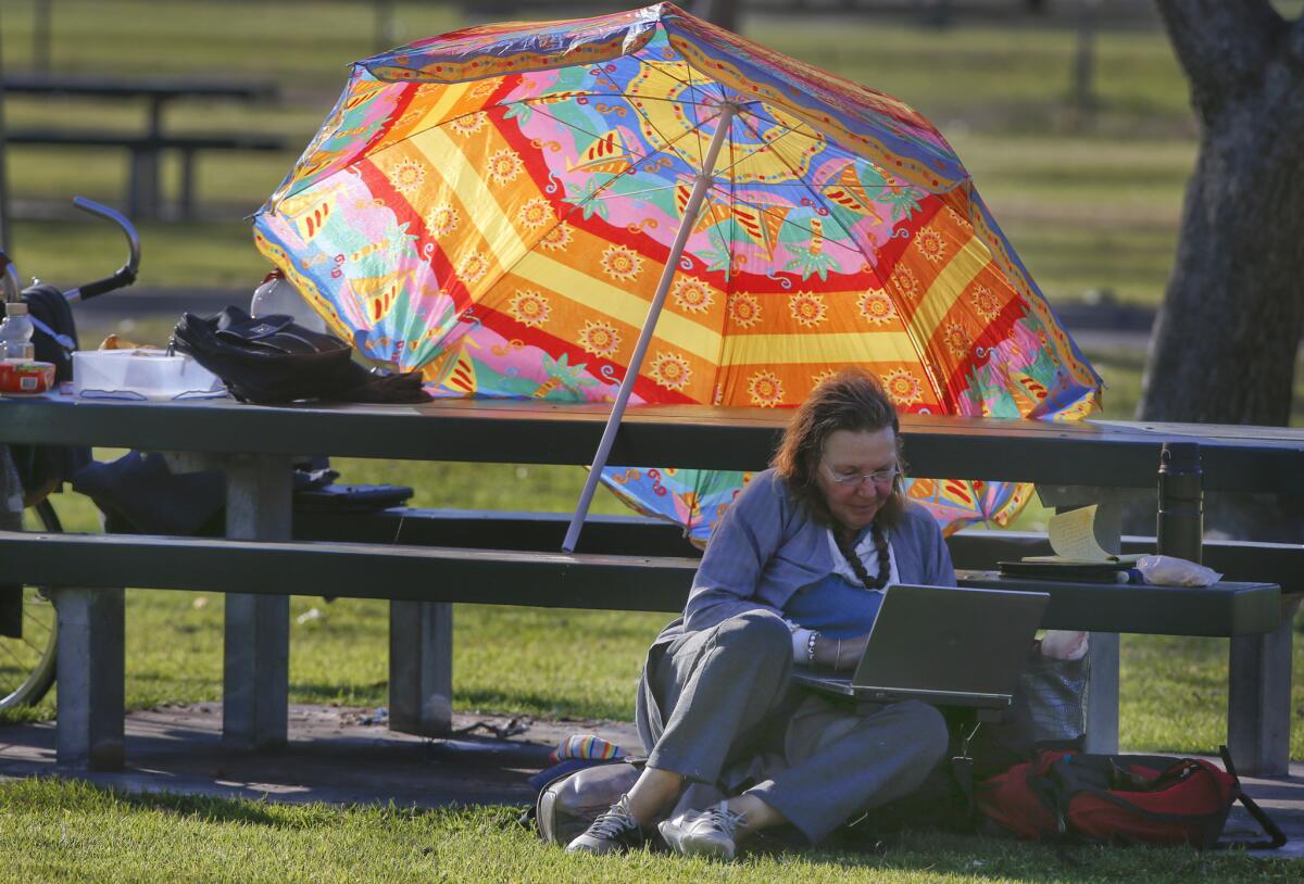Nancy Wood uses an umbrella to shade herself from 90-degree heat in Fountain Valley earlier this year.