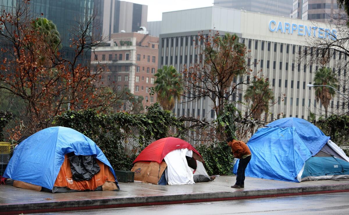 Homeless people shelter from the rain under camping tents in downtown Los Angeles on Tuesday, Dec. 22, 2015.