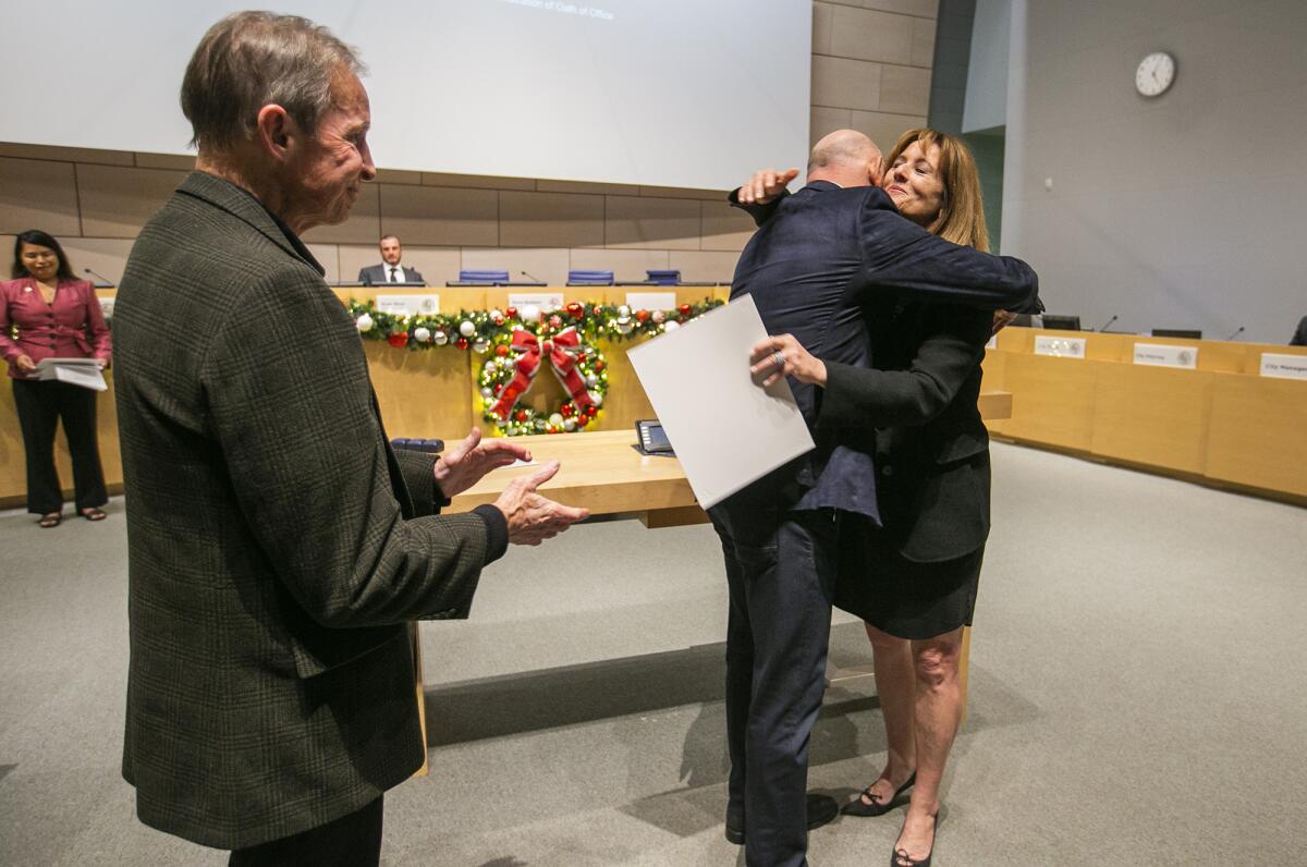Steve Rosansky, center, hugs his sister Robyn Grant as her husband David Grant, left, looks on.