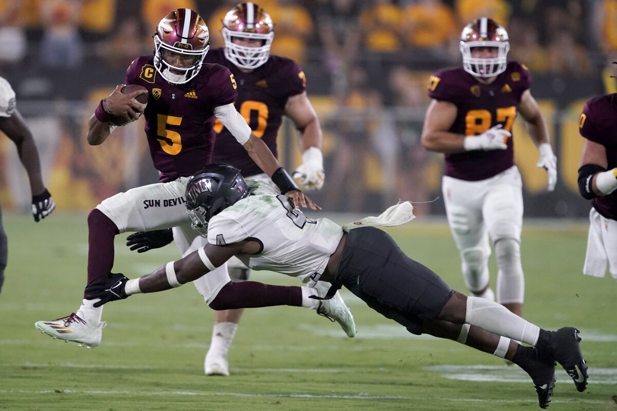 Arizona State quarterback Jayden Daniels (5) avoids the tackle of UNLV linebacker Jacoby Windmon (4) during the second half of an NCAA college football game, Saturday, Sept. 11, 2021, in Tempe, Ariz. (AP Photo/Matt York)