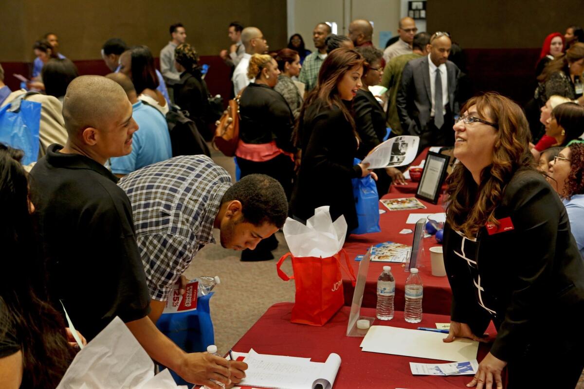 Patty Garcia, right, a store manager for J.C. Penney talks with job seekers at an employment fair in Carson.