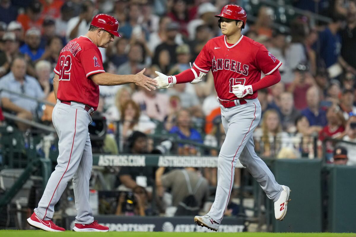 Angels star Shohei Ohtani is congratulated by third base coach Bill Haselman after hitting a home run.
