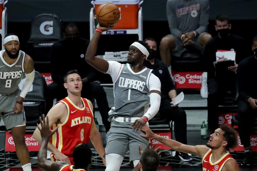 LOS ANGELES, CALIF. - MAR. 22, 2021. Clippers guard Reggie Jackson goes to the basket against a trio of Hawks defenders.