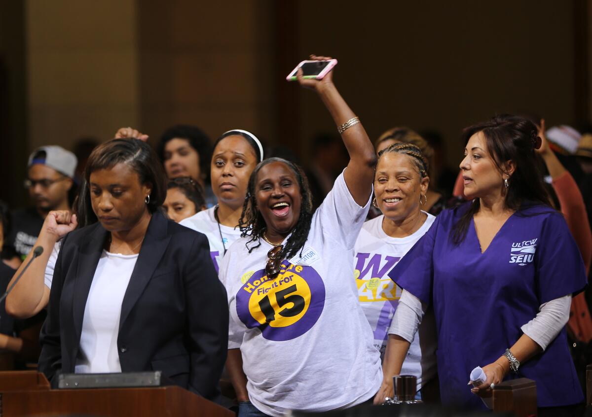 FILE - In this May 19, 2015, file photo, Laphonza Butler, President of SEIU ULTCW, the United Long Term Care Workers Union, far left, joins workers demanding the Los Angeles City Council to vote to raise the minimum wage. The council gave initial approval to raising minimum pay in the nation's second-largest city to $15 an hour by 2020. SEIU's state council announced an initiative Tuesday, Nov. 3, 2015, that would raise the minimum wage to $15 an hour by 2020 and require at least six paid sick days a year, double the number now offered to low-wage workers. Meanwhile, SEIU's United Healthcare Workers West already has been gathering signatures for a separate measure that would raise the minimum wage by $1 an hour until it hits $15 an hour in 2021. (AP Photo/Damian Dovarganes, File)