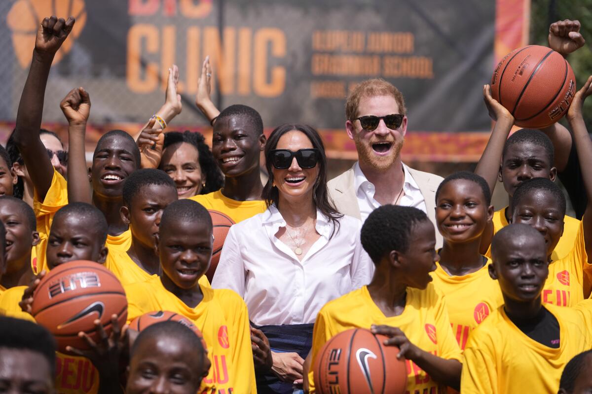 Prince Harry and Meghan pose for a photograph with children in Lagos, Nigeria.