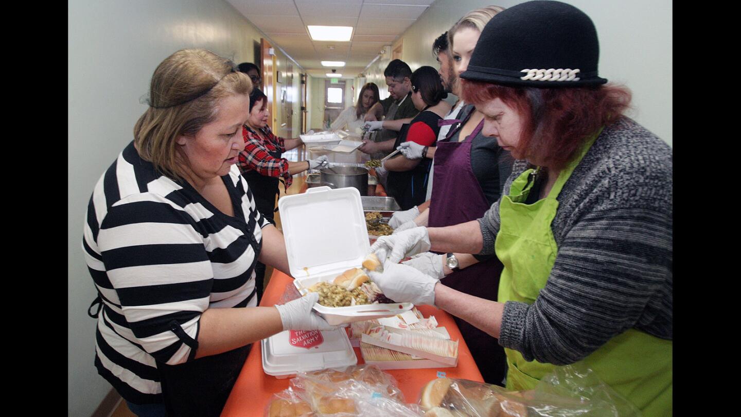 Julieta Obregon, of Glendale, holds up a container of food while Jackie Matthews places a dinner roll and some butter on top at the Salvation Army Glendale Corps and Community Center Thanksgiving dinner in Glendale on Thursday, Nov. 26, 2015.