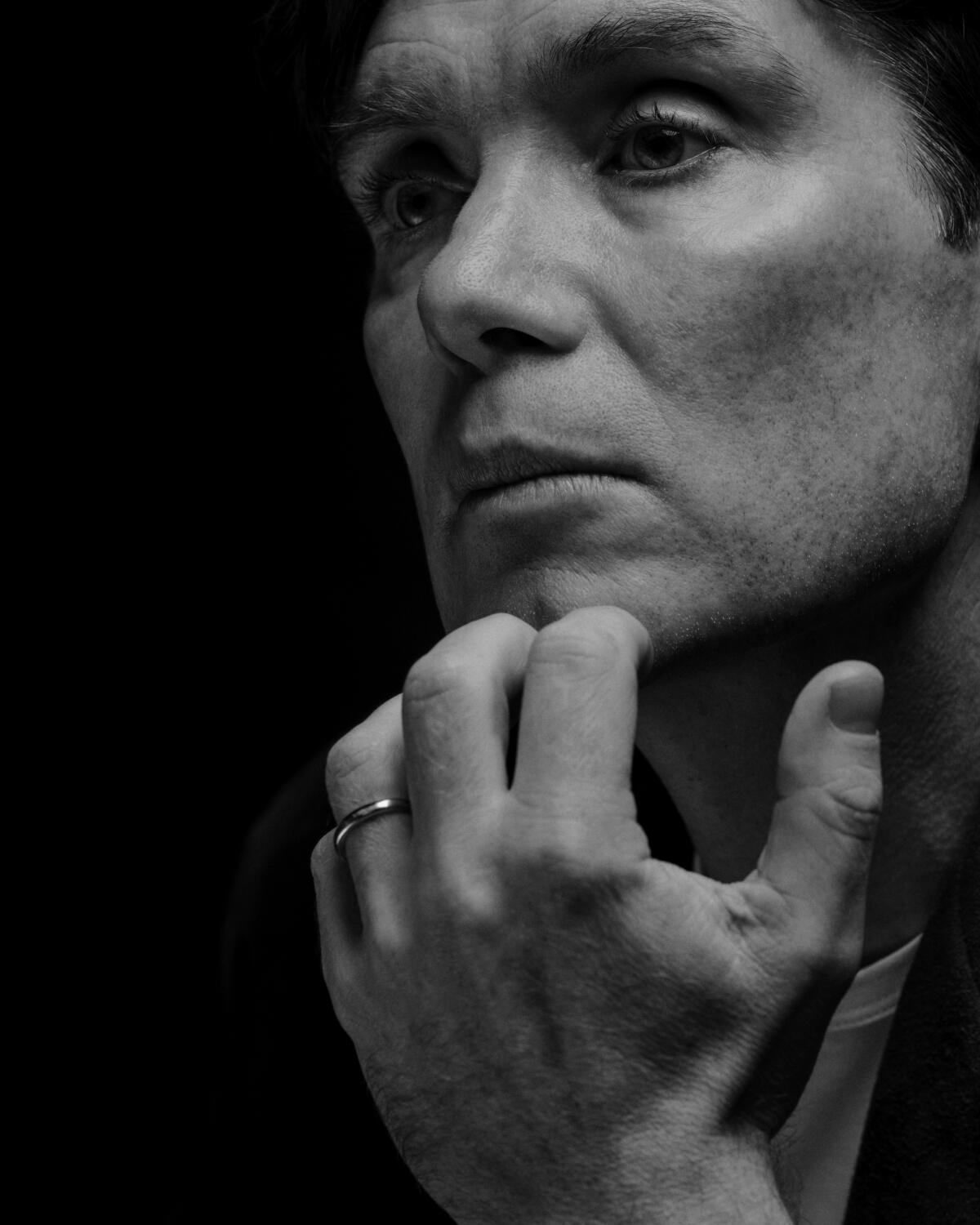 Cillian Murphy in a tight black-and-white frame touching his hand to his chin. 