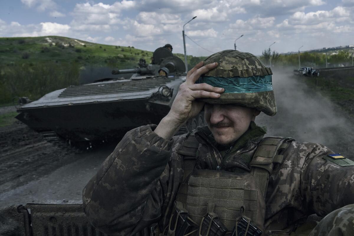 Ukrainian soldier holding onto his helmet