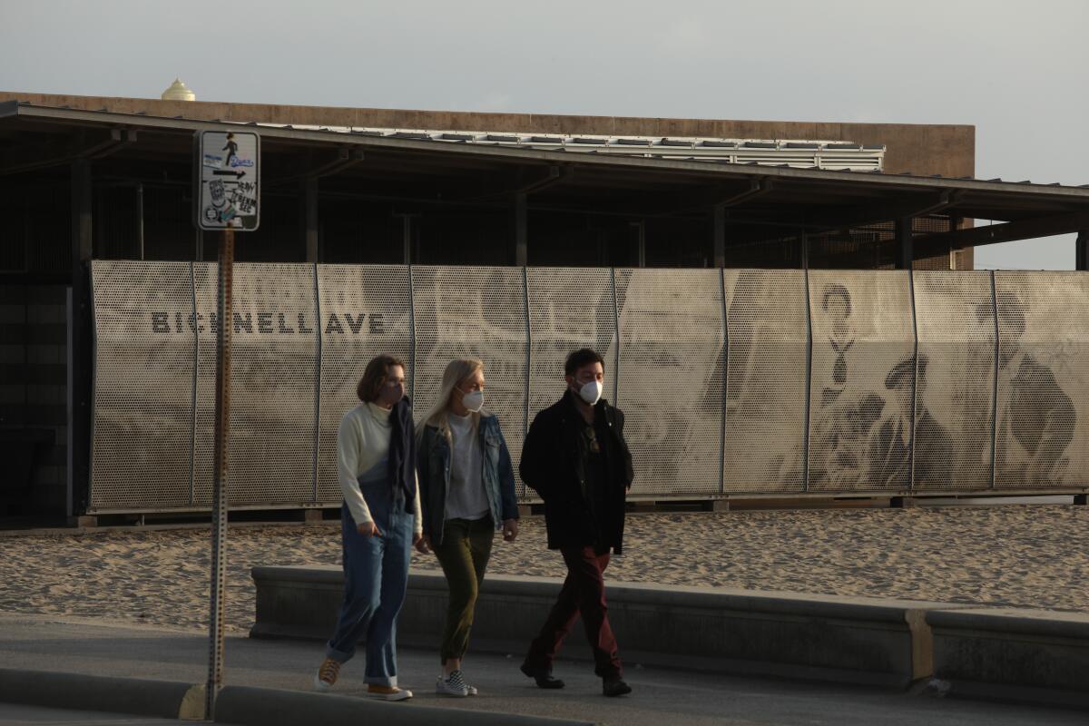 People walk along a path near a mural featuring Black people enjoying the beach.