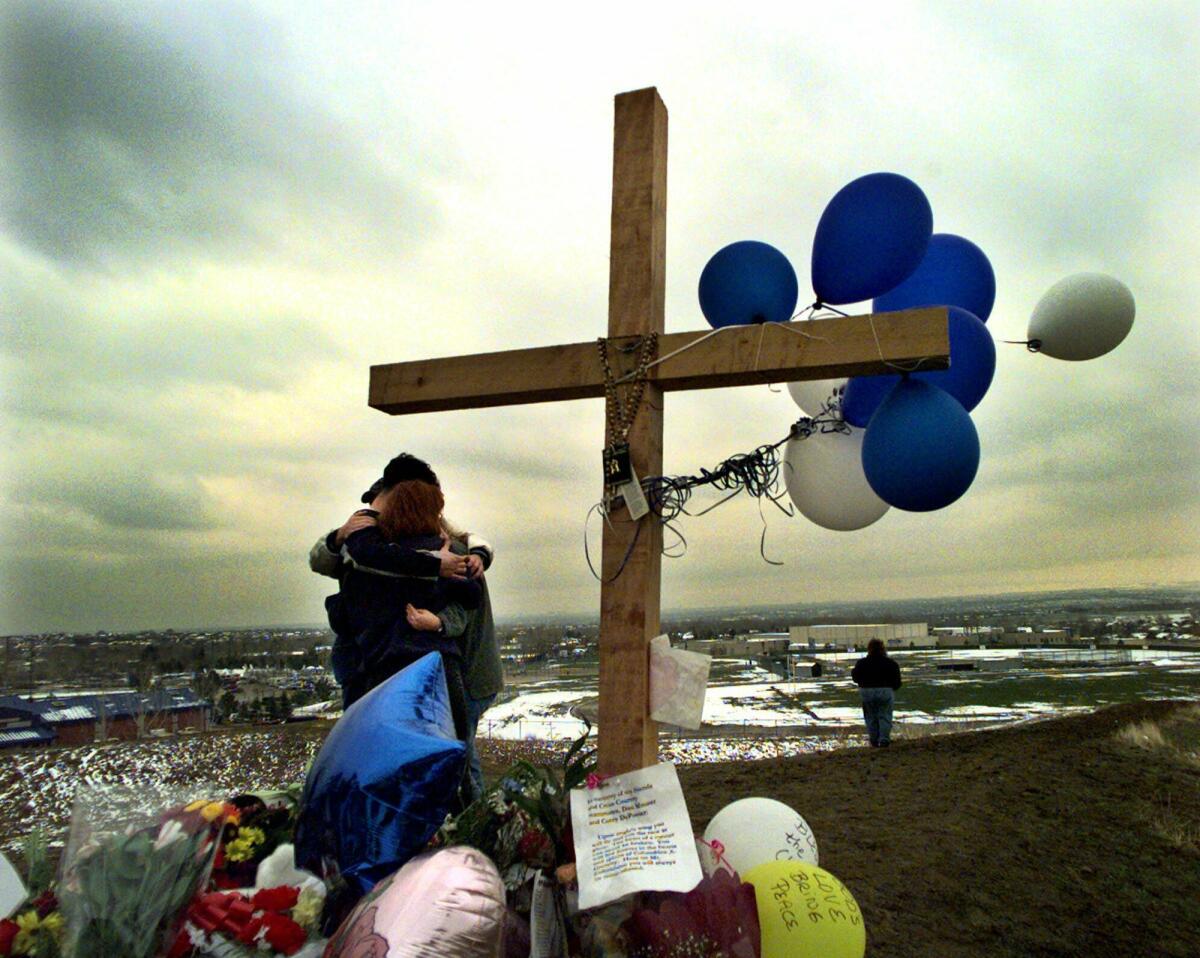 Students embrace at a memorial for victims of a school shooting. 