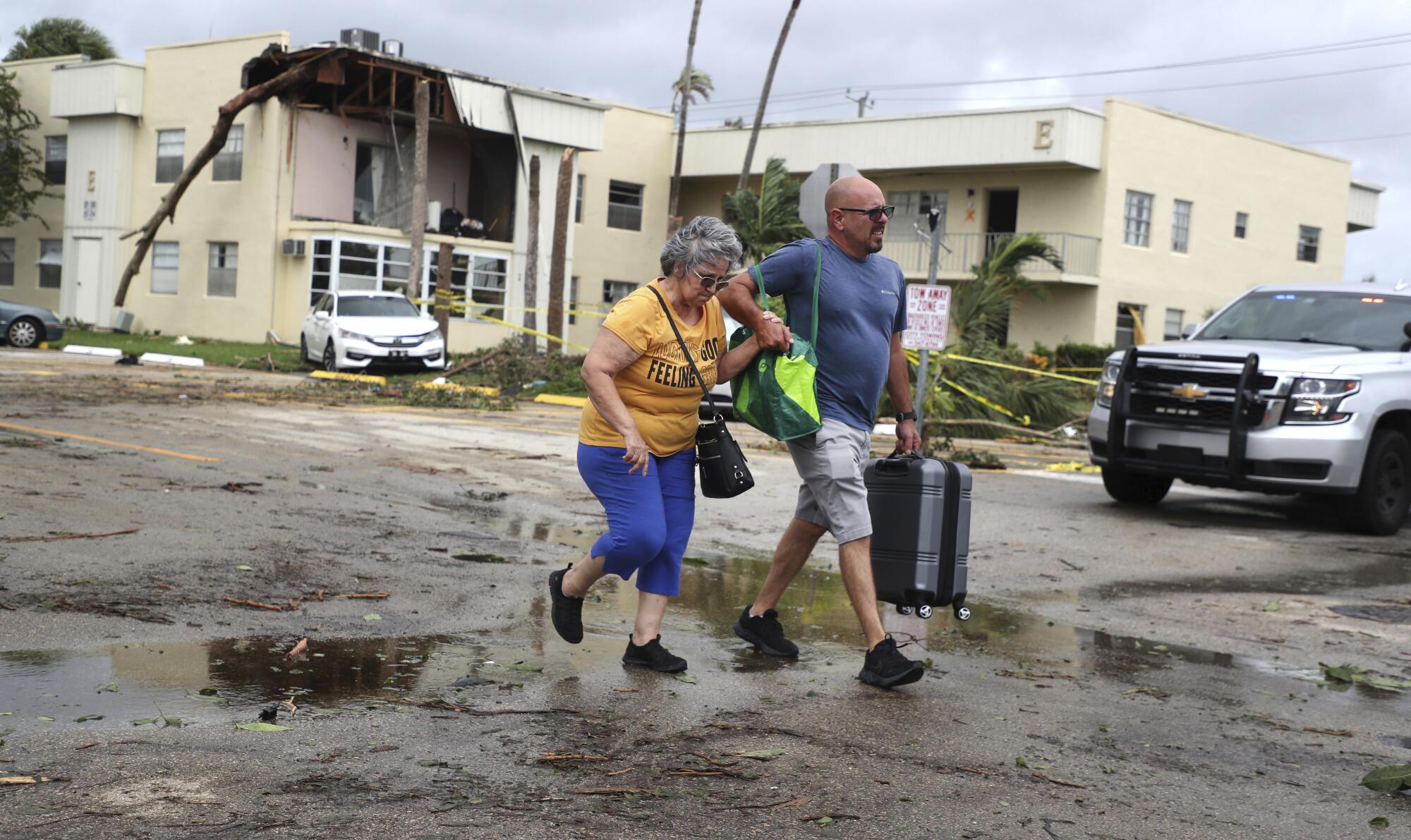 A woman is escorted by her son from a damaged home.