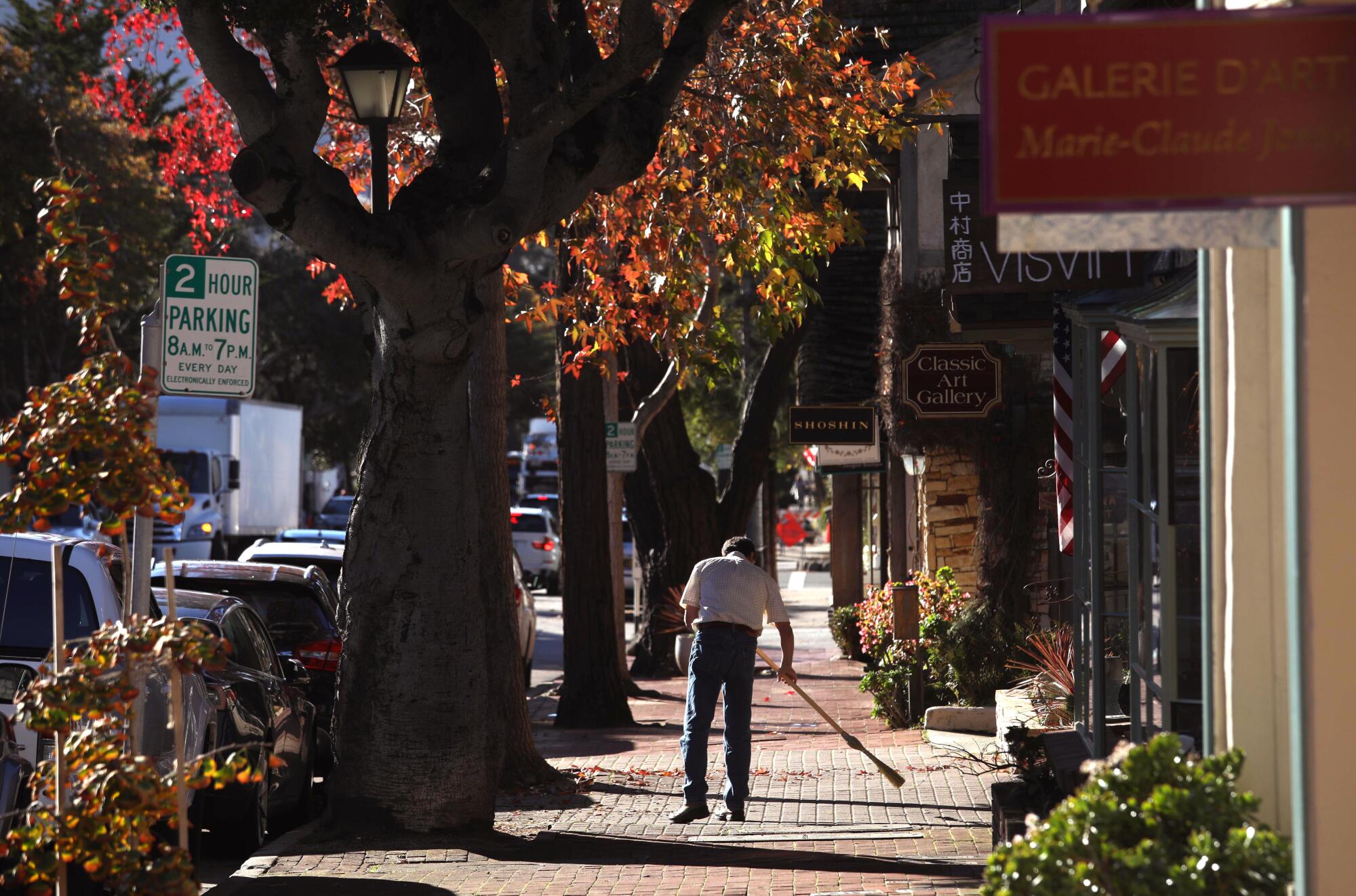 A man sweeps the sidewalk along San Carlos Street, between 5th & 6th streets, in downtown Carmel-by-the-Sea.