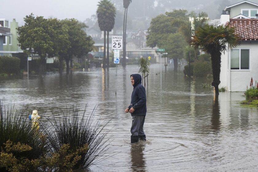A man wades through a flooded street in the Rio Del Mar neighborhood of Aptos, Calif., Monday, Jan. 9, 2023. (AP Photo/Nic Coury)