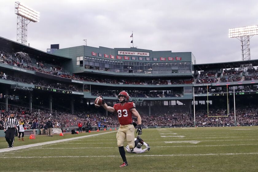 FILE - In this Nov. 17, 2018, file photo, Harvard wide receiver Jack Cook (83) raises the ball after crossing the goal line for a touchdown against Yale during the second half of an NCAA college football game at Fenway Park in Boston. The Ivy League has canceled all fall sports because of the coronavirus pandemic. (AP Photo/Charles Krupa, File)
