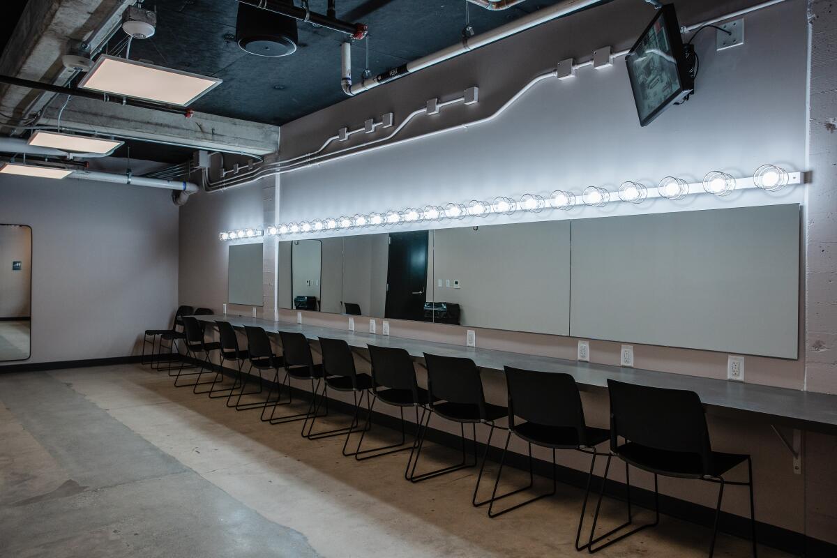 A theater dressing room with lights above mirrors.