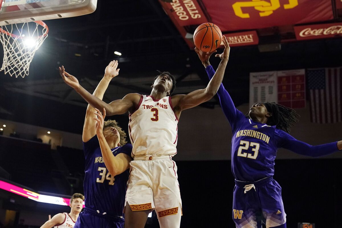 USC forward Vince Iwuchukwu grabs a rebound between Washington center Braxton Meah and guard Keyon Menifield.