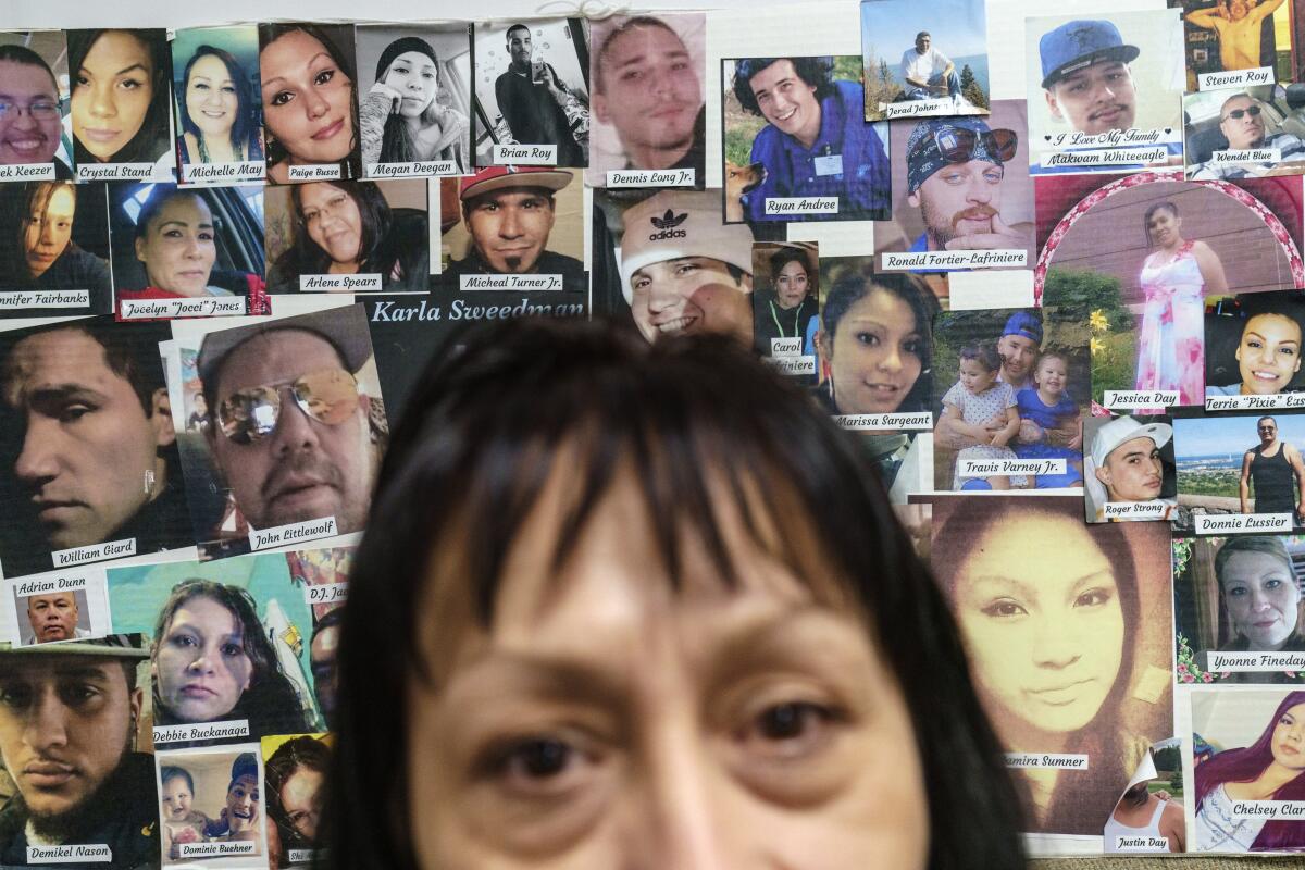 An employee at the Northwest Indian Community Development Center sits in front of a posterboard pasted with 49 faces.