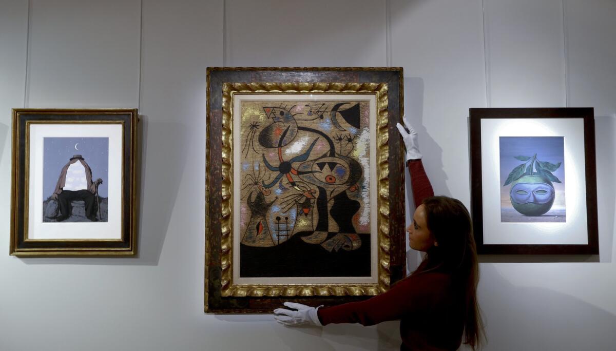 A Christie's employee displays a painting by Joan Miro, "L'echelle de l'evasion," at the auction rooms in London on Nov. 20.