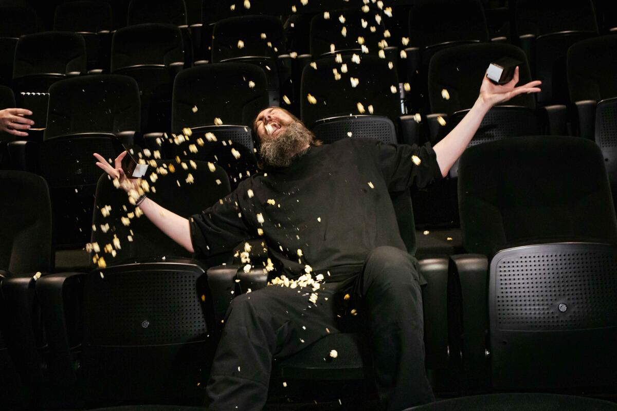 A man seated in a theater throws up his popcorn.