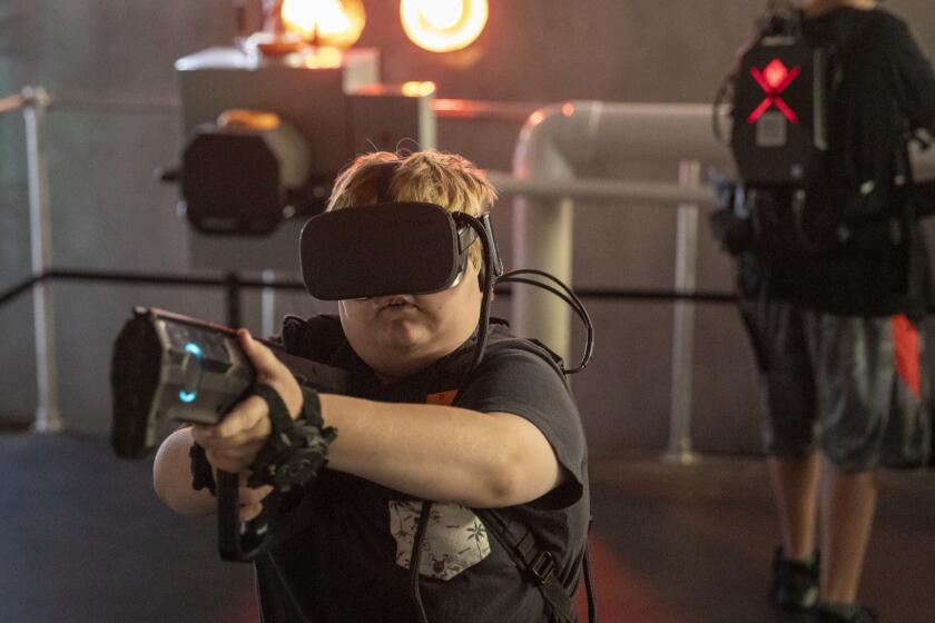 IRVINE, CALIF. -- FRIDAY, AUGUST 31, 2018: Chris Dion, not pictured, of Santa Ana, plays with his son, Jack Dion, center, 10, and Kyle Mendoza, right, 14, at the location-based virtual reality (VR) startup Spaces which is a new VR experience called "Terminator Salvation: Fight for the Future" in the former Red Robin building at the Irvine Spectrum Center. The Irvine Spectrum Center is spending heavily to keep people coming (a $200 million expansion), Photos taken at Irvine Spectrum Center in Irvine, Calif., on Aug. 31, 2018. (Allen J. Schaben / Los Angeles Times)